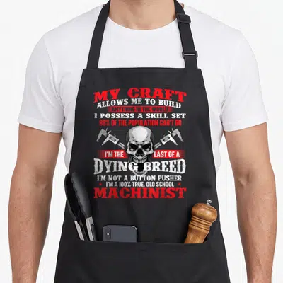 Build craft apron - Distressed skull with crossed calipers and red and white machinist typography — shown on a black cotton canvas apron against a white background