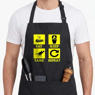 Eat survival apron - Yellow grid squares with steak, sleeper, dinosaur rider, and arrow icons below orange text — shown on a black cotton canvas apron against a white background