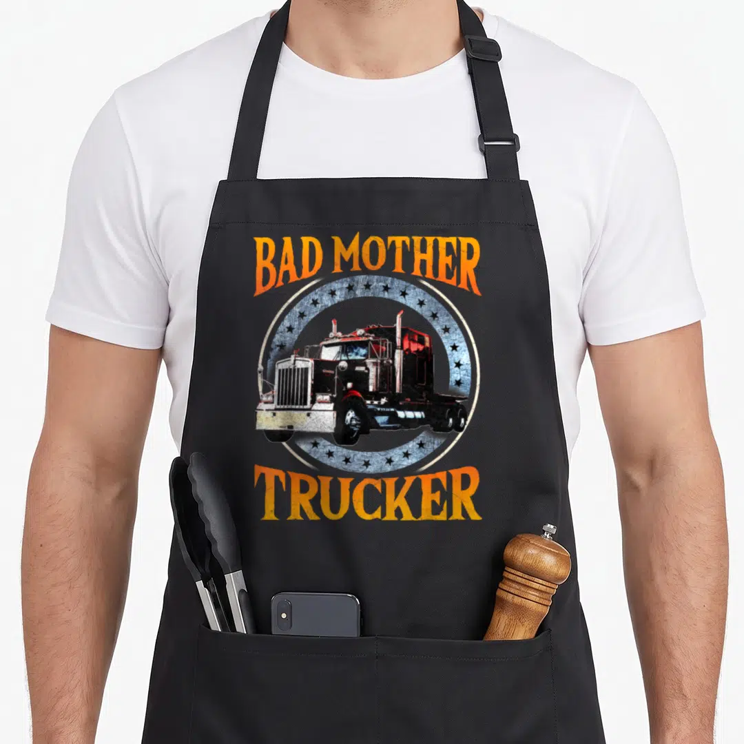 Truck tractor trailer apron - Arched orange text Bad Mother Trucker around a distressed black semi-truck on a blue star — shown on a black cotton canvas apron against a white background