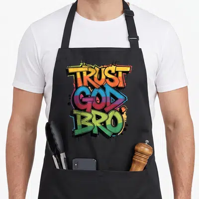 Humorous christian apron - Stacked graffiti text TRUST GOD BRO in orange blue green purple red with black drips — shown on a black cotton canvas apron against a white background