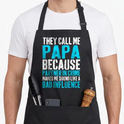 Call papa father day apron - White and cyan stacked text reading They Call Me Papa Because Partner In Crime Makes Me — shown on a black cotton canvas apron against a white background