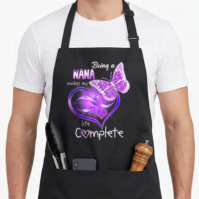 Complete nana aprons - Purple butterfly over heart with infinity symbol and scattered text — shown on a black cotton canvas apron against a white background