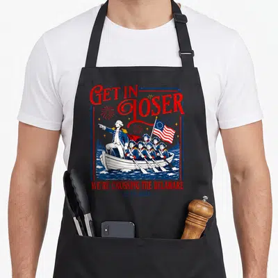 Crossing 4th of july apron - Get In Loser George Washington boat scene with fireworks in red white blue distressed style — shown on a black cotton canvas apron against a white background