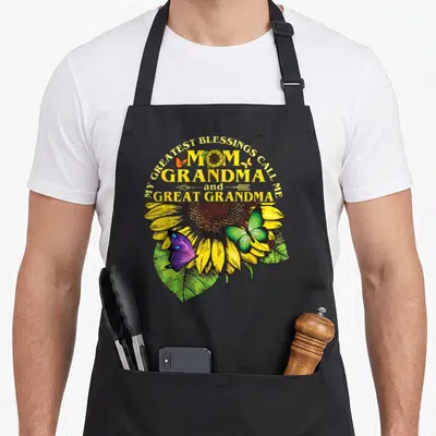 Greatest great grandma apron - Sunflower and purple butterfly graphic with Mom Grandma Great Grandma text — shown on a black cotton canvas apron against a white background