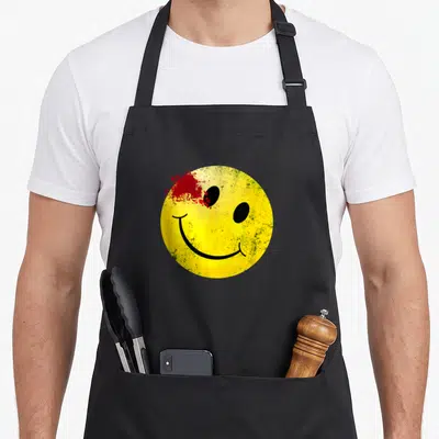 Smiling bloody apron - Yellow smiley face with red blood splatter on top left and distressed texture — shown on a black cotton canvas apron against a white background