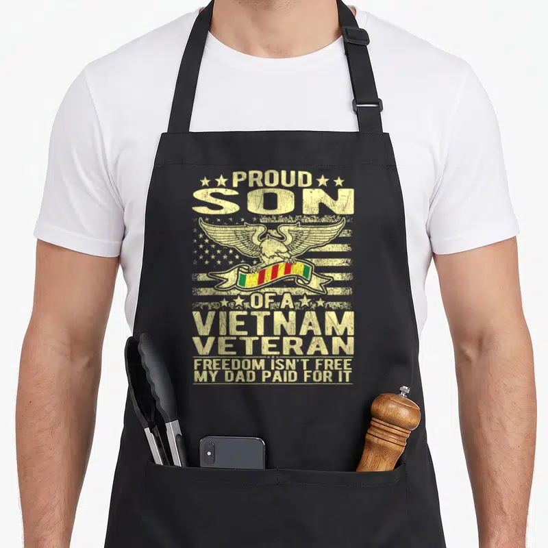Freedom eagle dad apron - Distressed eagle holding red yellow green ribbon over stars stripes with stacked text reading — shown on a black cotton canvas apron against a white background