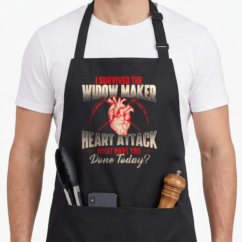 Widow maker apron - Red anatomical heart with two scythes and survival text — shown on a black cotton canvas apron against a white background