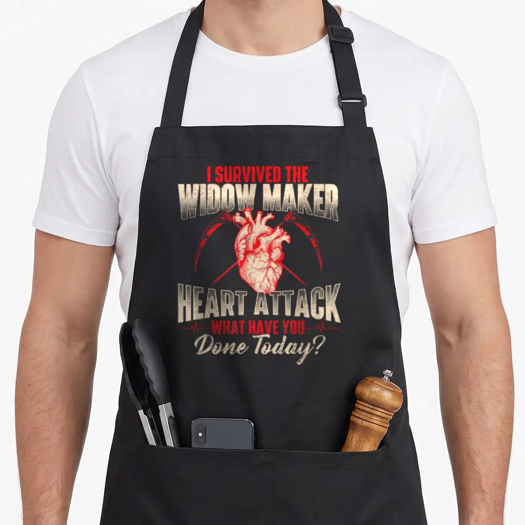 Widow maker apron - Red anatomical heart with two scythes and survival text — shown on a black cotton canvas apron against a white background