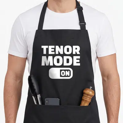 Tenor choir apron - White TENOR MODE ON text above toggle switch graphic on black fabric — shown on a black cotton canvas apron against a white background