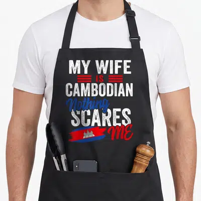 Cambodia wife apron - Stacked white red and blue text My Wife Is Cambodian Nothing Scares Me with brush stroke flag — shown on a black cotton canvas apron against a white background