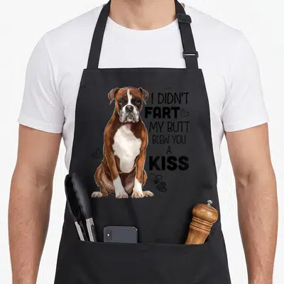 Funny boxer dog apron - Realistic brown white boxer sits next to stacked text I didn't fart my butt blew you a kiss — shown on a black cotton canvas apron against a white background