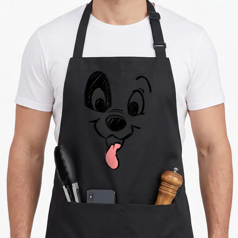 Dalmatian face apron - Stylized black line art dog face with pink tongue hanging out — shown on a black cotton canvas apron against a white background