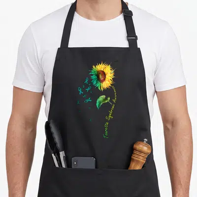 Tourette sunflower apron - Realistic sunflower with teal ribbons and curved Tourette Syndrome Awareness text in yellow — shown on a black cotton canvas apron against a white background