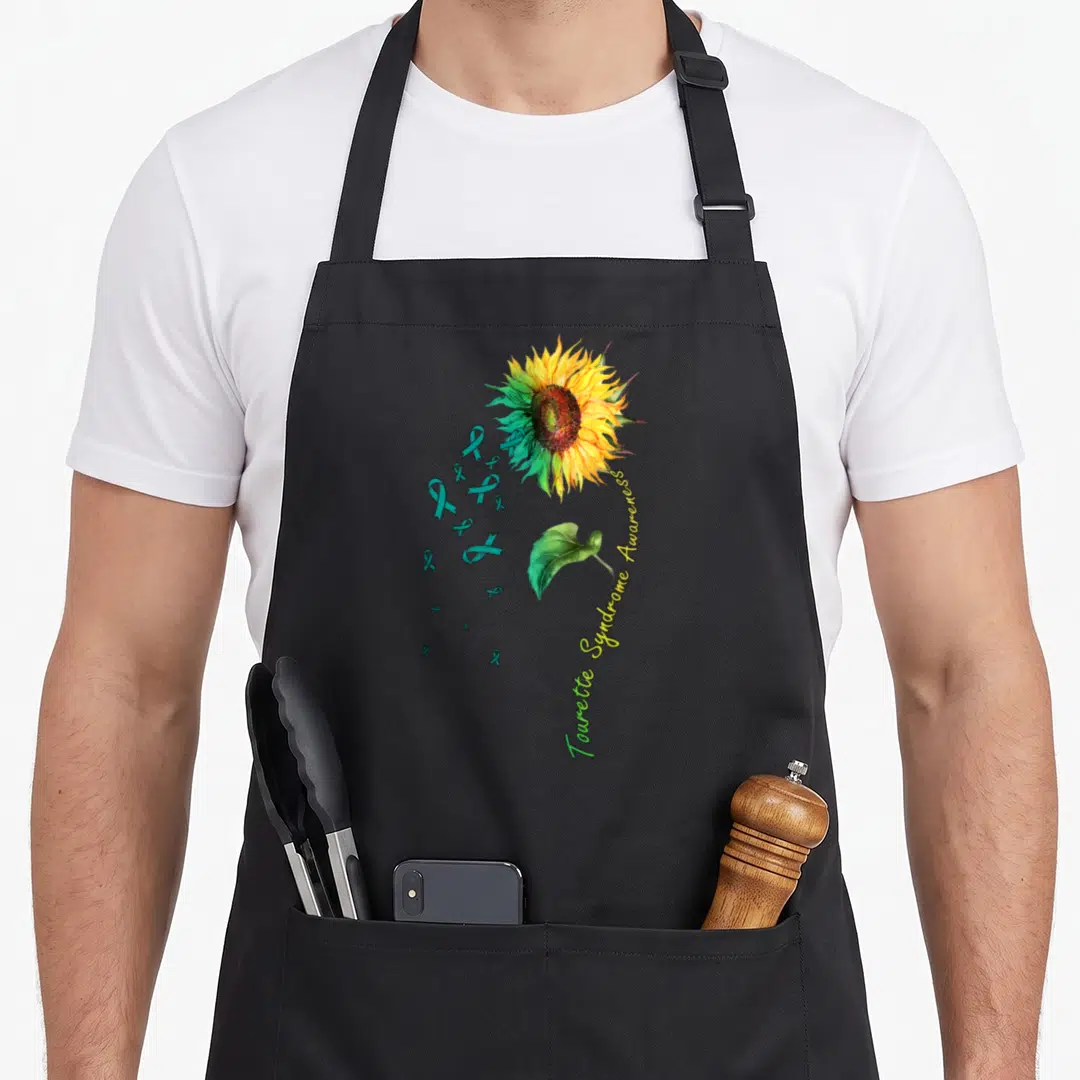 Tourette sunflower apron - Realistic sunflower with teal ribbons and curved Tourette Syndrome Awareness text in yellow — shown on a black cotton canvas apron against a white background