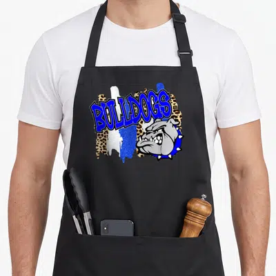 Funny bulldog school apron - Arched blue BULLDOGS text above a grey bulldog head with leopard and glitter splashes — shown on a black cotton canvas apron against a white background