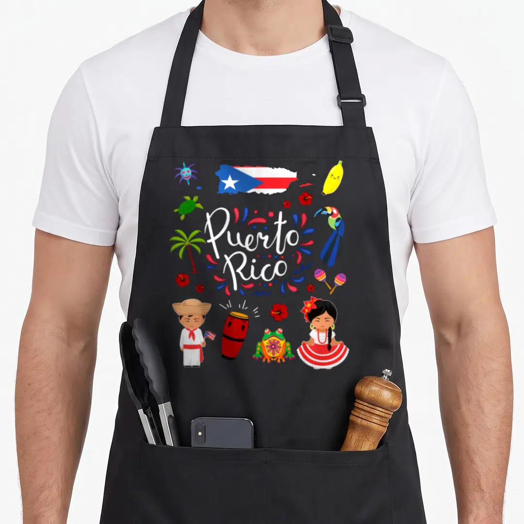 Puerto chef outfit with apron - Puerto Rico script surrounded by toucan, frog, flag, and dancers in cartoon style — shown on a black cotton canvas apron against a white background