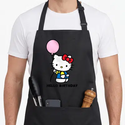 Birthday apron with pockets - Hello Kitty holding pink balloon with HELLO BIRTHDAY text below in white pink red blue — shown on a black cotton canvas apron against a white background