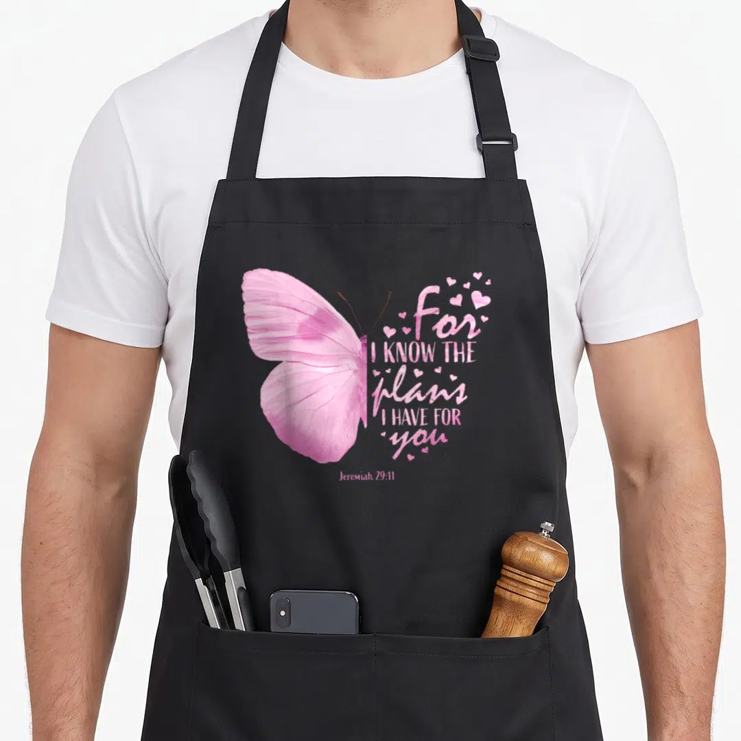 Religious christian bible verse apron - Pink butterfly with for I know the plans I have for you text and hearts — shown on a black cotton canvas apron against a white background