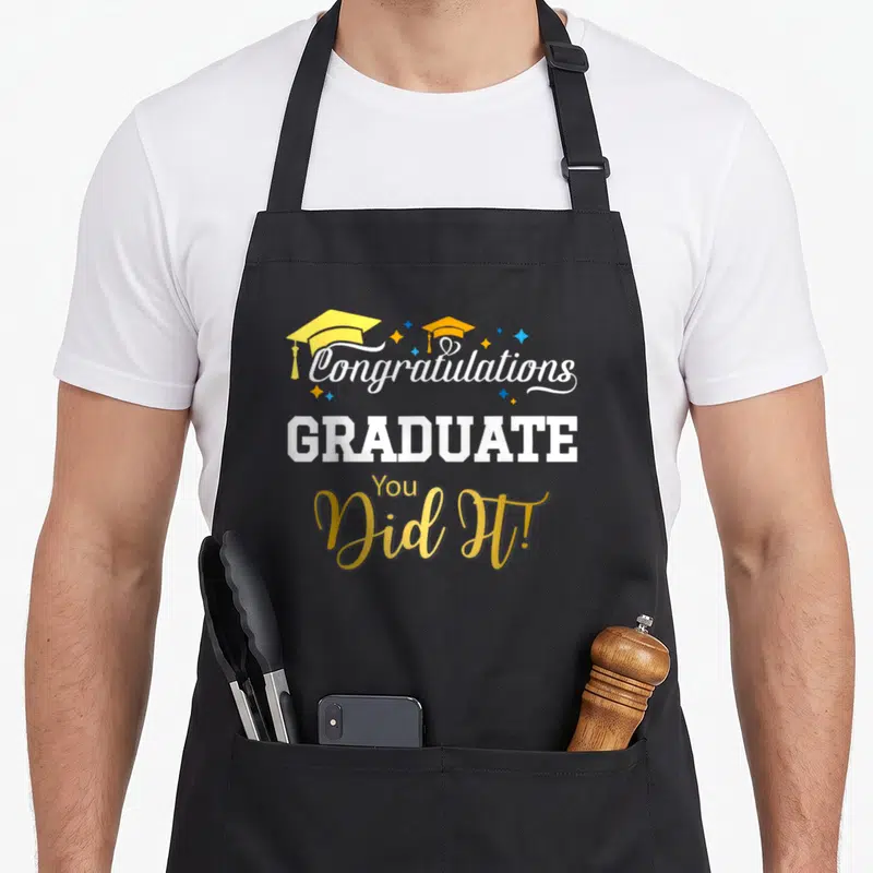 Class congrat apron - shows two caps and stars with Congratulations GRADUATE You Did It text — shown on a black cotton canvas apron against a white background