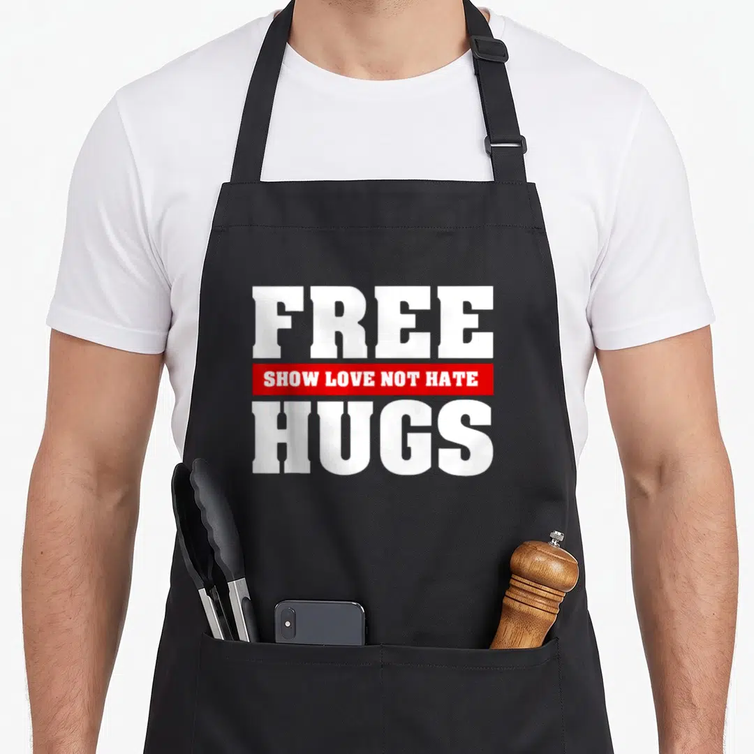 Free festival apron - White text free and hugs with red banner showing love not hate — shown on a black cotton canvas apron against a white background