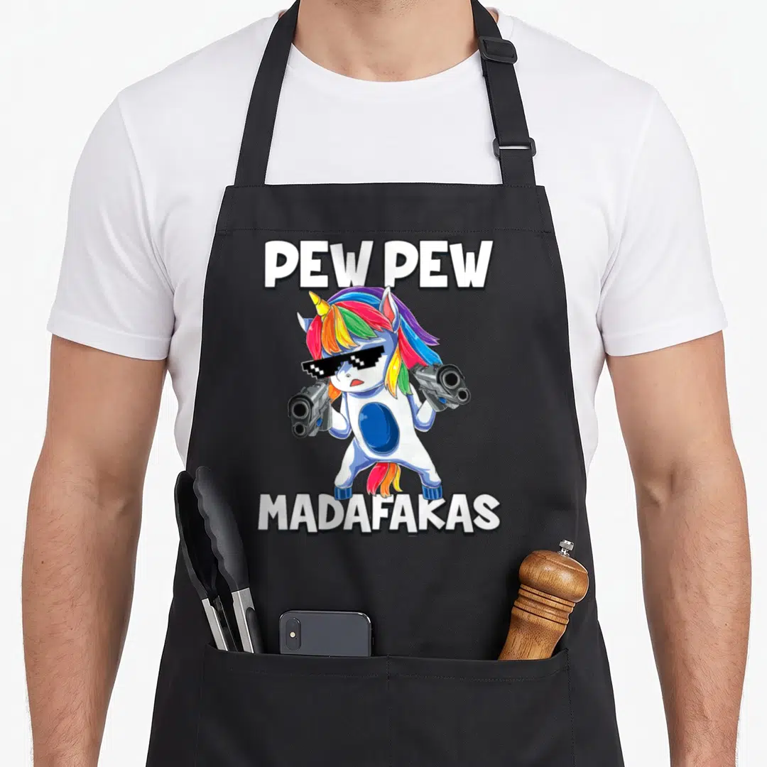 Pew unicorn apron - Cartoon unicorn with pixelated sunglasses holding two silver guns with PEW PEW MADAFAKAS text — shown on a black cotton canvas apron against a white background