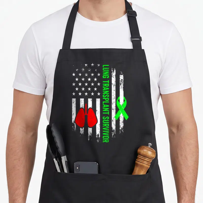 Lung transplant organ apron - Distressed white flag with red lungs, green ribbon, and vertical green text — shown on a black cotton canvas apron against a white background