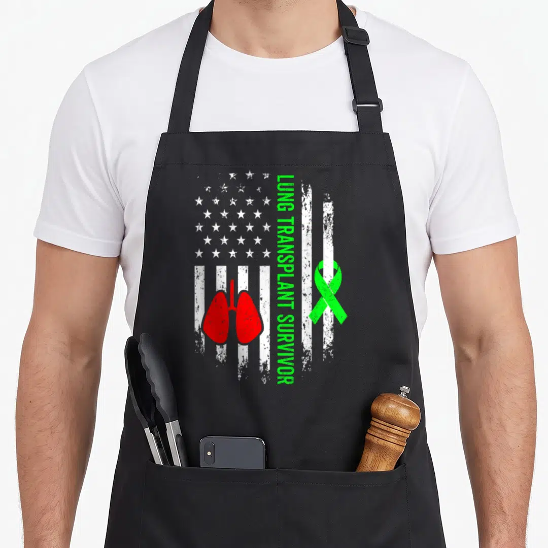Lung transplant organ apron - Distressed white flag with red lungs, green ribbon, and vertical green text — shown on a black cotton canvas apron against a white background