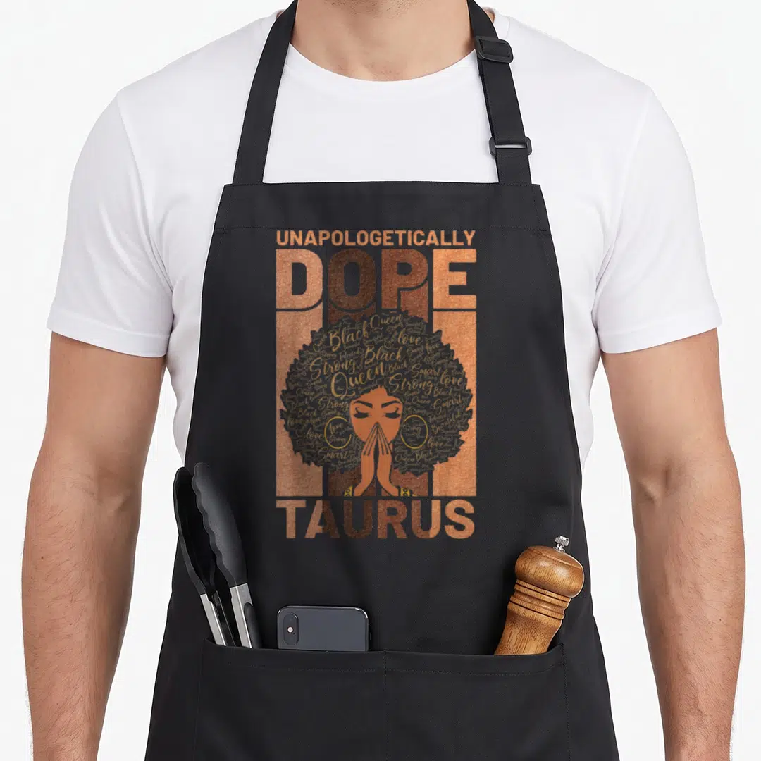 History taurus aprons - Unapologetically Dope Taurus woman with grey afro and orange brown typography — shown on a black cotton canvas apron against a white background