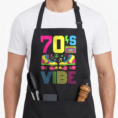 Theme 70s apron - Roller skates cassette tape and 70'S VIBE text in pink yellow blue and green — shown on a black cotton canvas apron against a white background