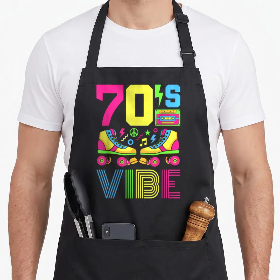 Theme 70s apron - Roller skates cassette tape and 70'S VIBE text in pink yellow blue and green — shown on a black cotton canvas apron against a white background