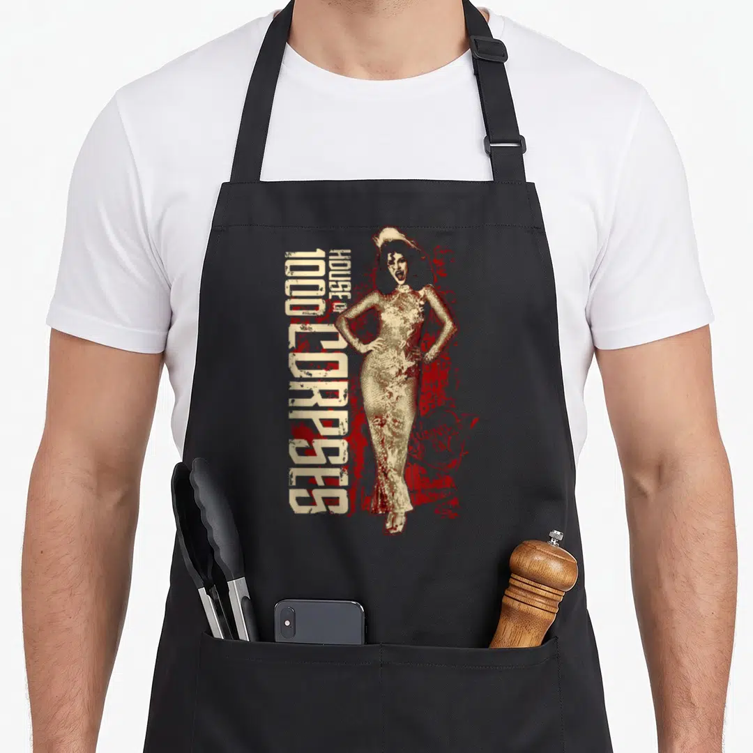Rob stage apron - Vertical House of 1000 Corpses text beside a distressed beige woman with red splatter background — shown on a black cotton canvas apron against a white background