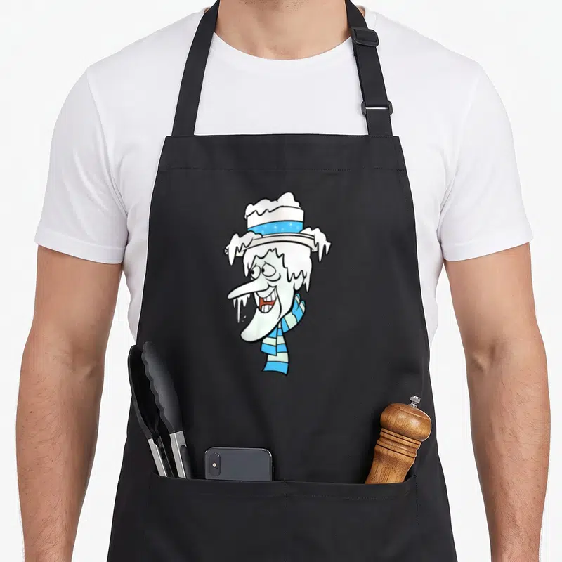 Snow santa claus apron - Cartoon snowman head with blue star hat and icicles in white, blue, black — shown on a black cotton canvas apron against a white background