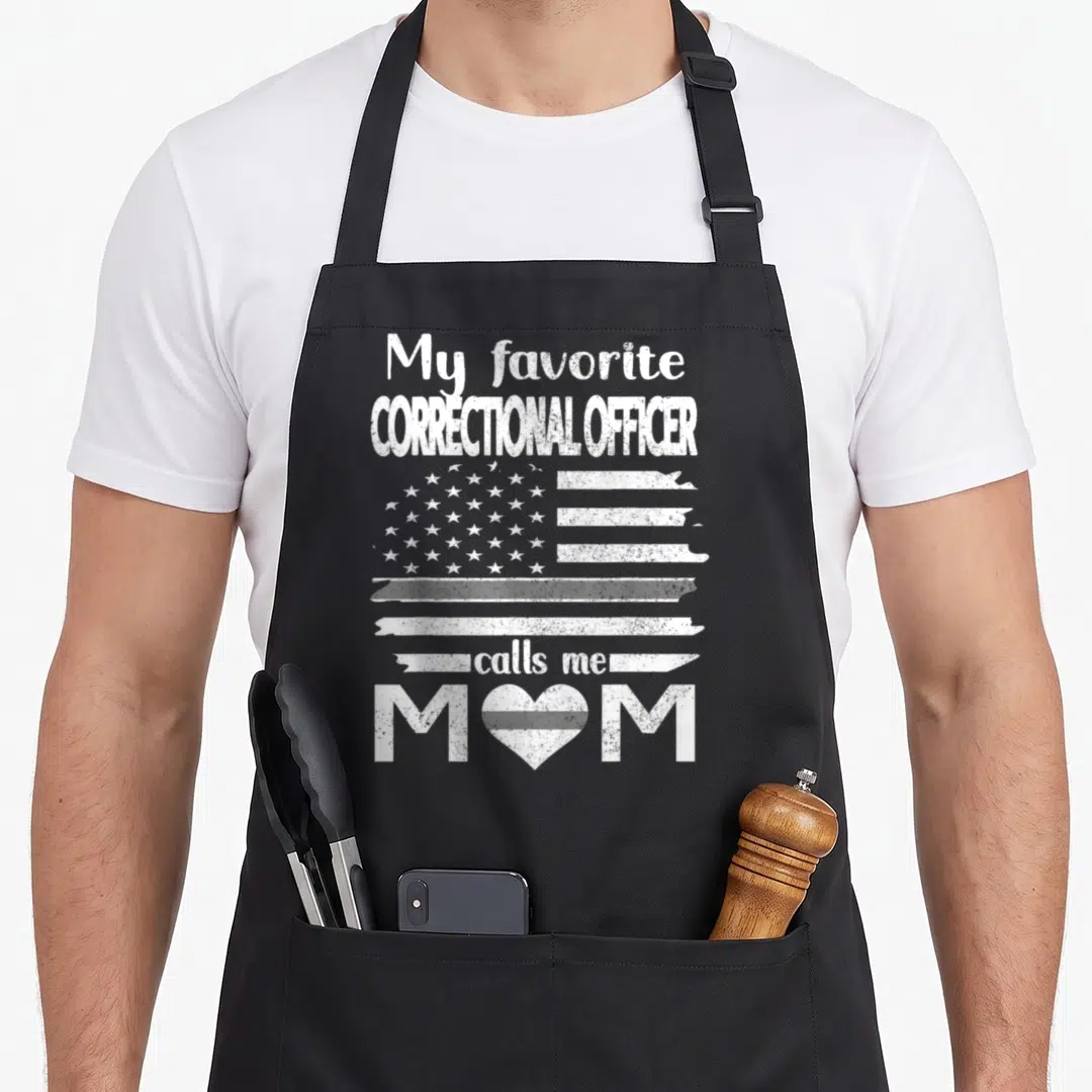 Correctional call mom apron - Distressed white USA flag with text My favorite Correctional Officer calls me Mom — shown on a black cotton canvas apron against a white background