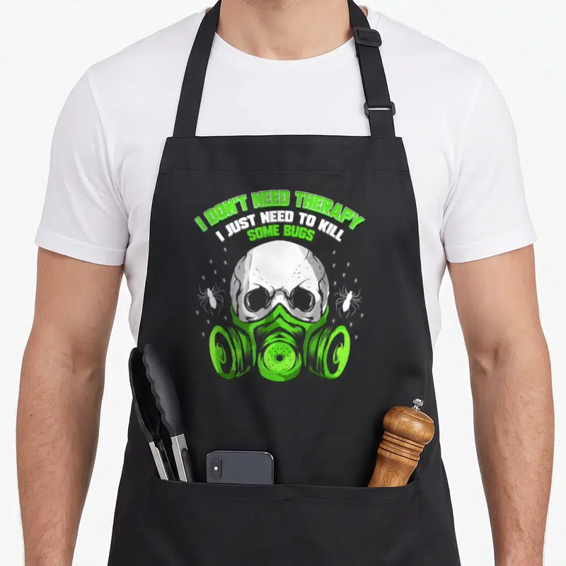 Exterminator bed apron - Arched text above a skull in a green gas mask flanked by two white spiders — shown on a black cotton canvas apron against a white background