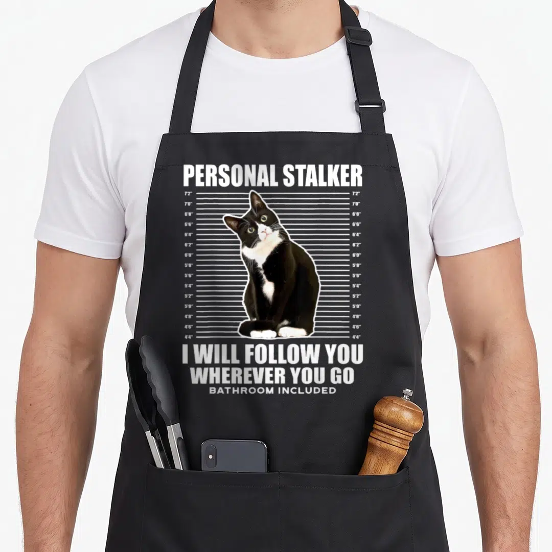 Personal tuxedo apron - Black and white cat sitting in front of a height chart with text Personal Stalker and I Will — shown on a black cotton canvas apron against a white background