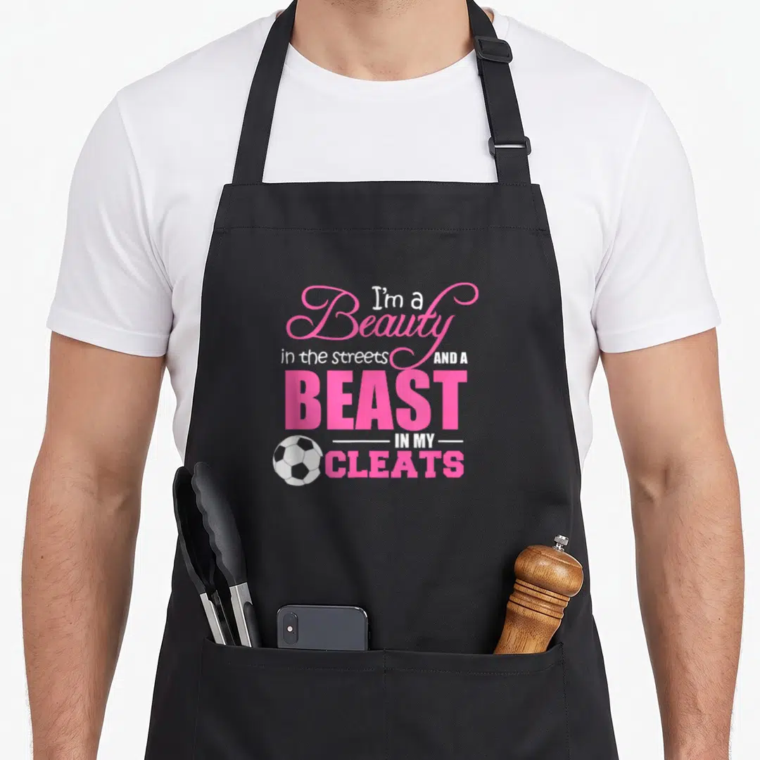 Street beauty apron - Pink and white typography with a soccer ball positioned next to the bottom text lines — shown on a black cotton canvas apron against a white background