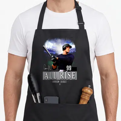 Aaron baseball apron - Photo of Aaron Judge holding a bat with 99 and ALL RISE text below — shown on a black cotton canvas apron against a white background