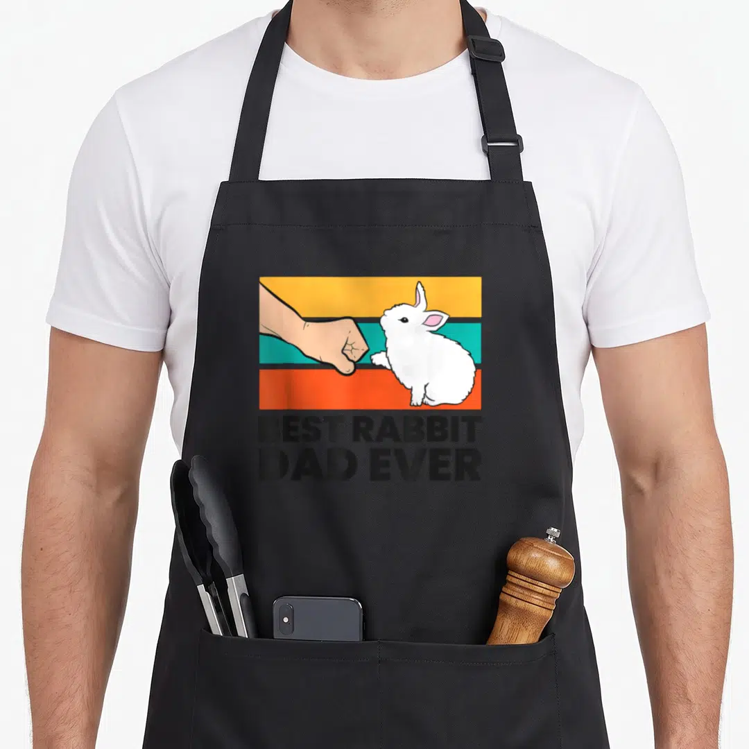 Bunny rabbit apron - White rabbit and hand fist bumping over yellow teal orange stripes with black text — shown on a black cotton canvas apron against a white background