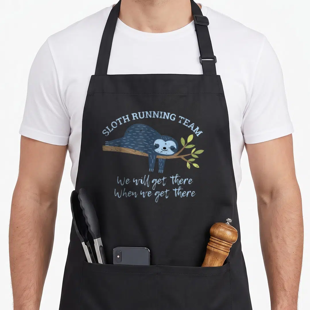 Jogging sloth apron - Blue cartoon sloth hanging from branch with SLOTH RUNNING TEAM text — shown on a black cotton canvas apron against a white background