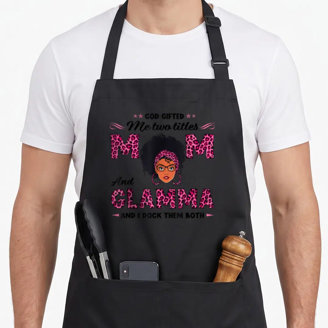 Glamma mother's day aprons - Cartoon woman face with pink leopard print text reading Mom and Glamma — shown on a black cotton canvas apron against a white background