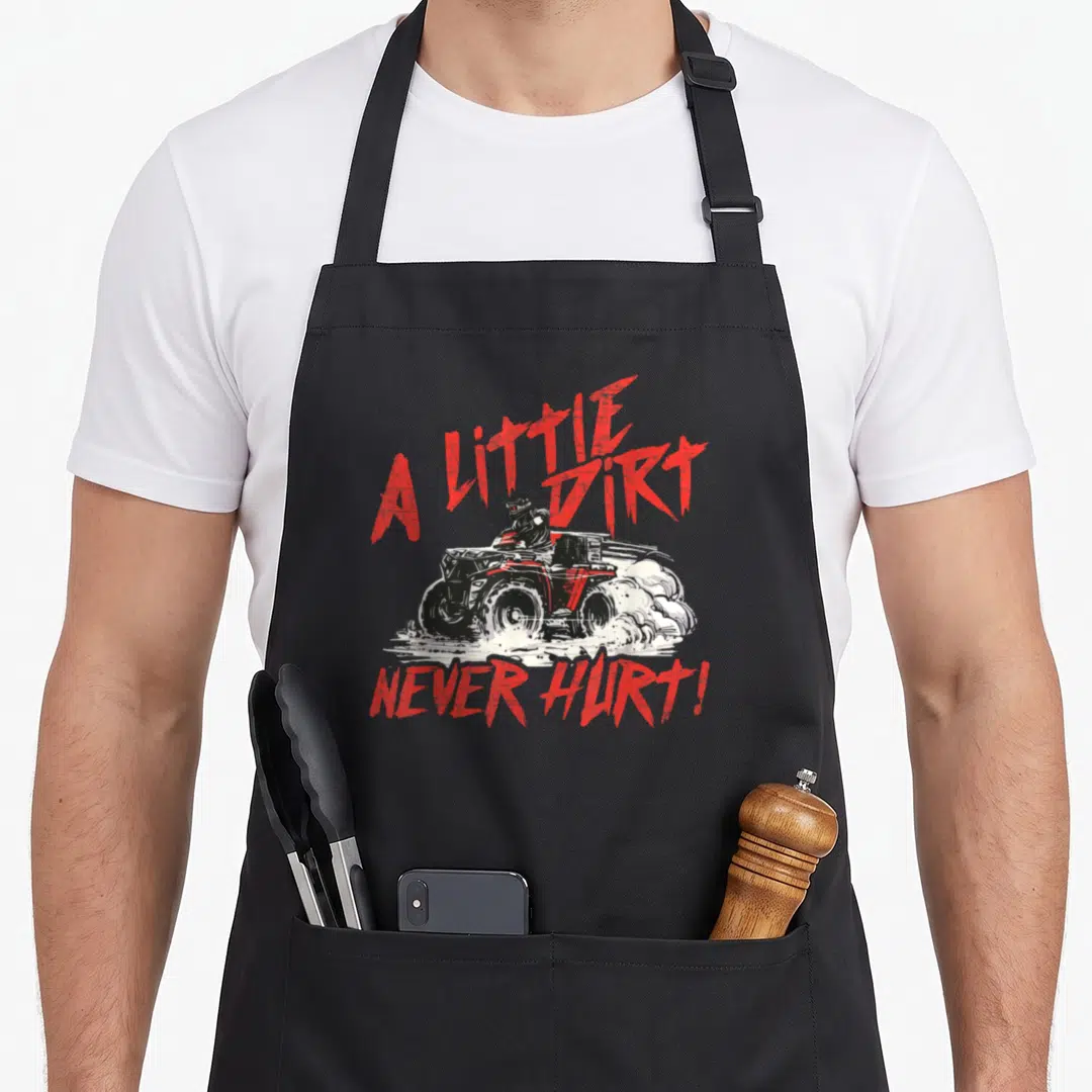 Dirt wheeler guy apron - Red and white distressed ATV rider with text A Little Dirt Never Hurt — shown on a black cotton canvas apron against a white background