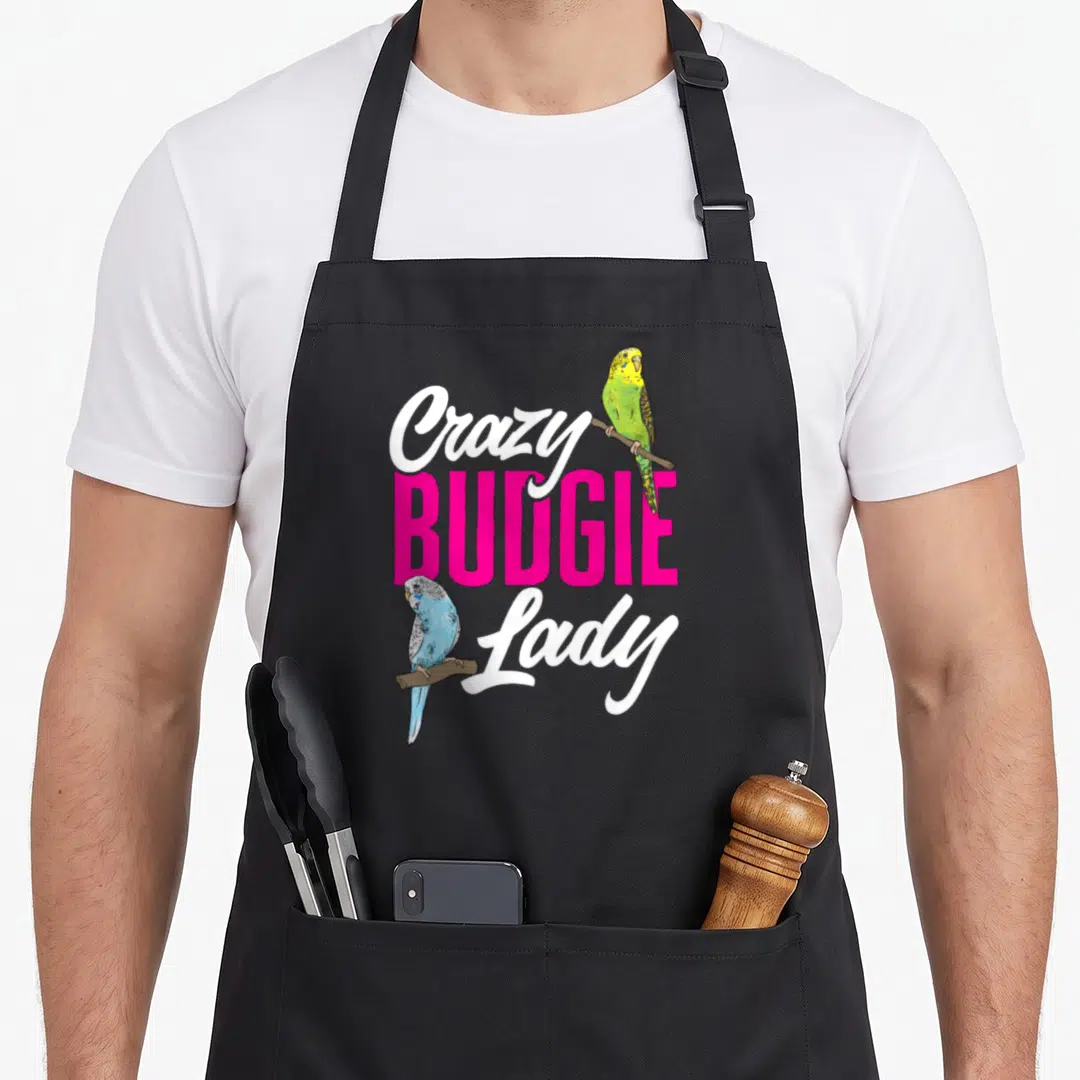 Parakeet budgie bird apron - Crazy BUDGIE Lady text with green and blue budgies on wooden perches — shown on a black cotton canvas apron against a white background