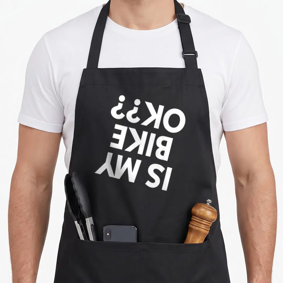 Dirt bmx bike apron - White rotated text reading IS MY BIKE OK?? on grey background — shown on a black cotton canvas apron against a white background