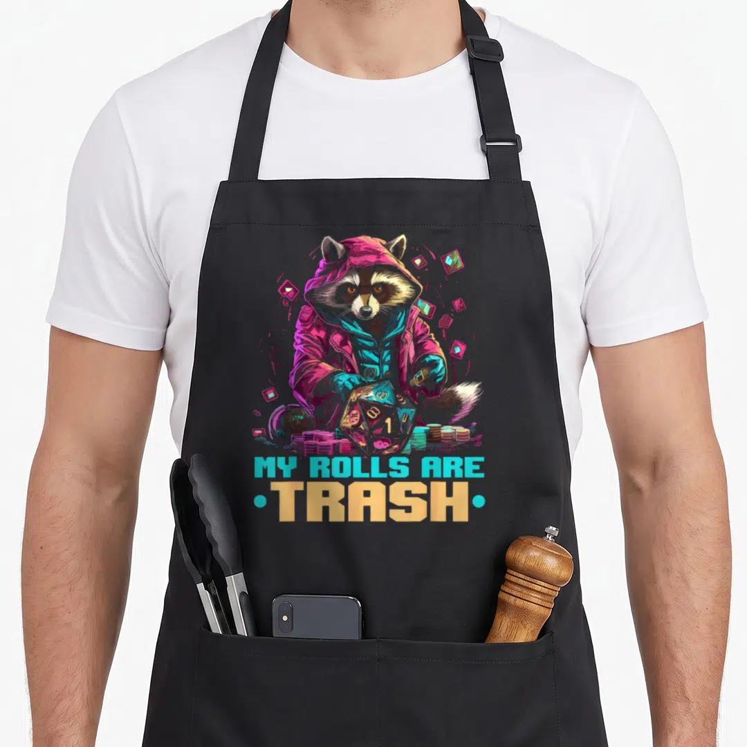 Role playing gaming apron - Raccoon in hoodie holding d20 die with MY ROLLS ARE TRASH text in neon colors — shown on a black cotton canvas apron against a white background