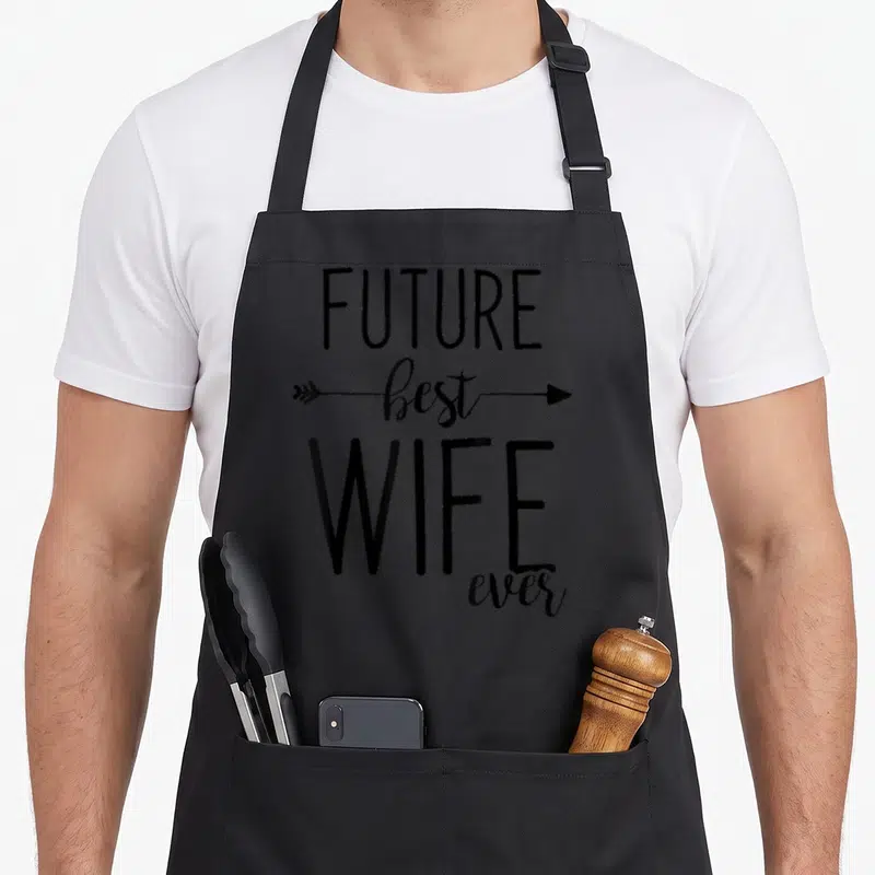 Future wife apron - Black stacked text FUTURE best WIFE ever with horizontal arrow behind best — shown on a black cotton canvas apron against a white background