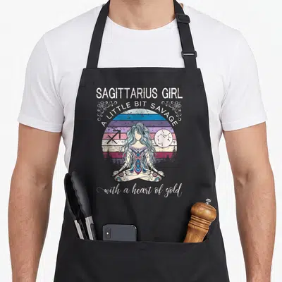 Sagittarius december birthday apron - Cartoon woman in lotus pose with striped sun, Sagittarius symbol — shown on a black cotton canvas apron against a white background