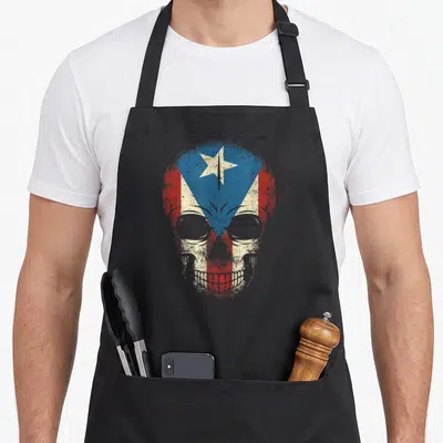 Puerto skull apron - Distressed skull filled with red white and blue flag layout — shown on a black cotton canvas apron against a white background