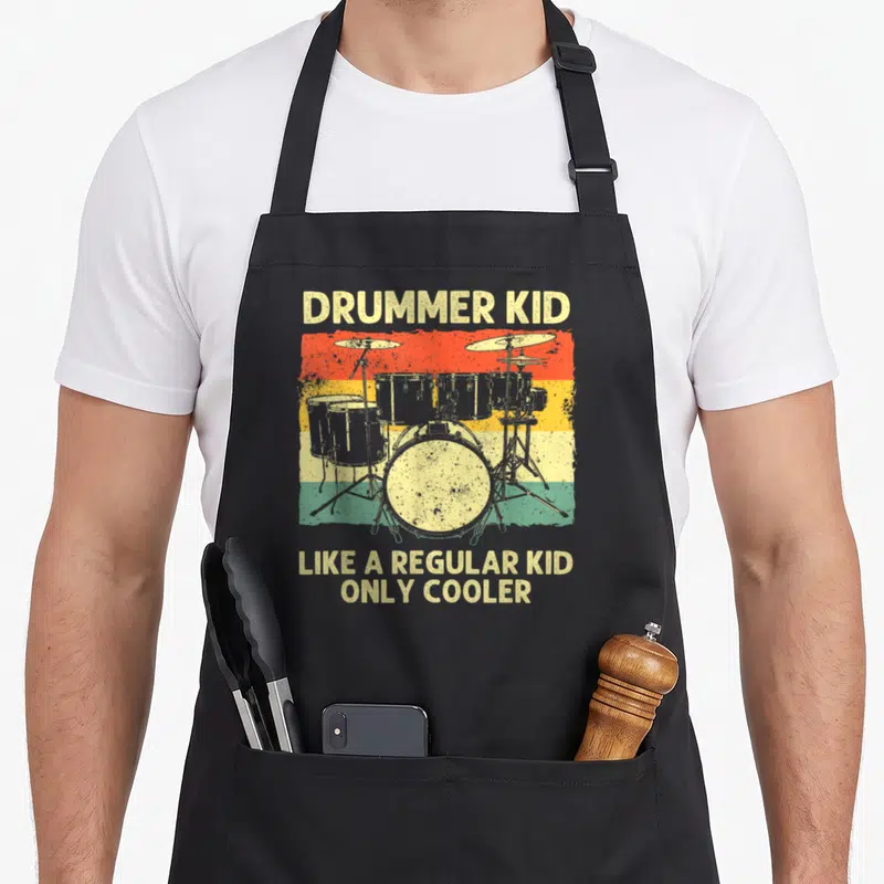 Drumline drum apron - Retro drum kit on red yellow green stripes with text DRUMMER KID LIKE A REGULAR KID ONLY COOLER — shown on a black cotton canvas apron against a white background