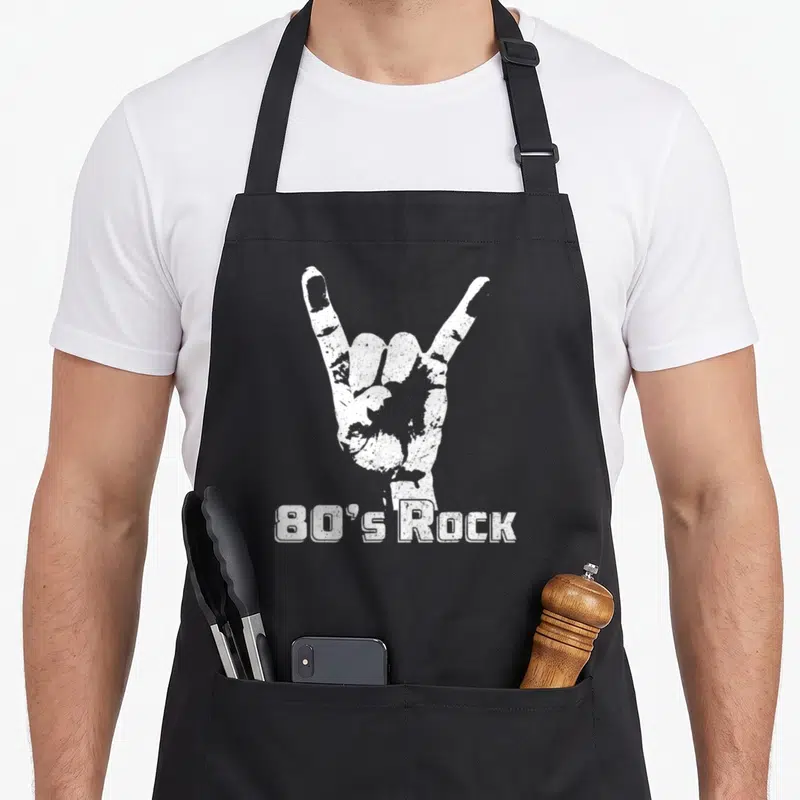 Rock 80s apron - White distressed hand rock sign above 80's Rock text — shown on a black cotton canvas apron against a white background