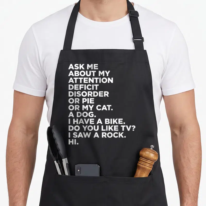 Ask adhd apron - White stacked text reading Ask Me About My Attention Deficit Disorder Or Pie Or My Cat A Dog I Have — shown on a black cotton canvas apron against a white background